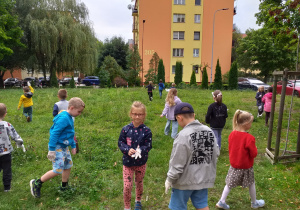 Dzieci zbierają śmieci na pobliskim trawniku.