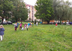 Dzieci starają się jak najlepiej oczyścić trawnik z wszelkich śmieci.