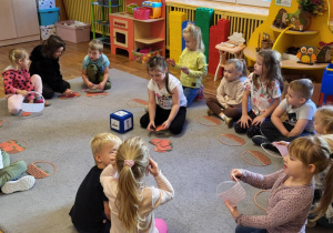 Dziewczynka wkłada do koszyka tyle jabłek, ile wskazuje cyfra na kostce.