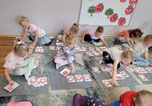 Dzieci z grupy Słoneczka wypełniają jabłka odpowiednimi kształtami.