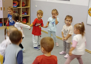Przedszkolaki w kole tańczą do słyszanej muzyki.