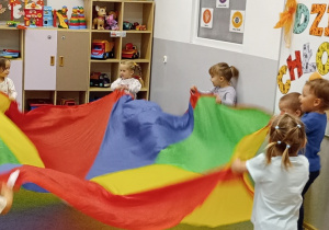 Dzieci z grupy Biedronki w trakcie zabawy chustą animacyjną.