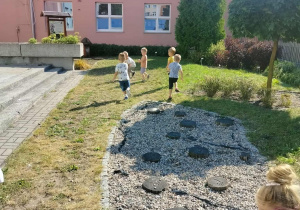 Dzieci biegają po ogrodzie przedszkolnym.