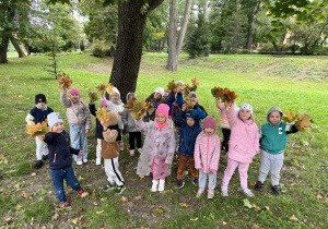 Dzieci pozują w parku z jesiennymi bukietami z liści.