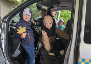 Dzieci pozują przy radiowozie Straży Miejskiej.