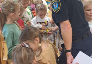 Pani ze straży miejskiej częstuje dzieci cukierkami.