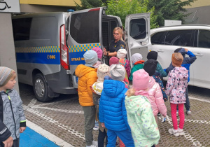 Pani ze straży miejskiej pokazuje dzieciom radiowóz.