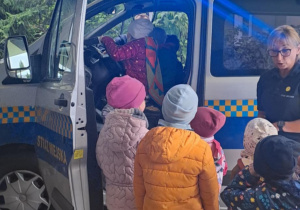 Dzieci oglądają radiowóz straży miejskiej.