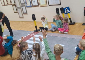 Na zdjęciu widać Panią ze Straży Miejskiej rozdającą dzieciom naklejki z uśmiechniętą buźką.