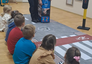 Pani ze straży miejskiej pokazuje edukacyjną kostkę podczas zajęć o bezpieczeństwie.