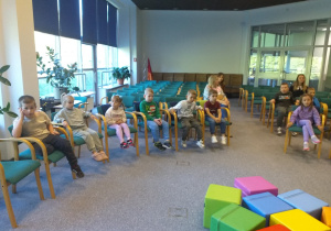 Zdjęcie przedstawia dzieci słuchające bajki czytanej przez panią bibliotekarkę