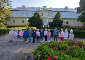 Dzieci robią sobie pamiątkowe zdjęcie na tle Dworku Olszewskich podczas odpoczynku na drodze do Biblioteki.