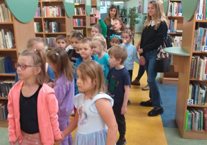 Zdjęcie przedstawia dzieci zdumiewające się na widok tak wielu książek w Bibliotece.