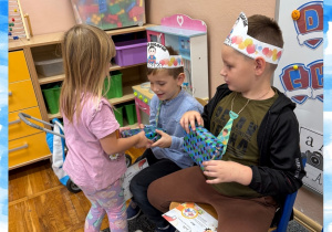 Dziewczynka wręcza prezent z okazji Dnia Chłopaka koledze z grupy