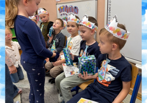 Dziewczynka wręcza prezent z okazji Dnia Chłopaka koledze z grupy