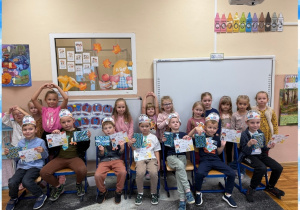 Cała grupa pozuje do zdjęcia z prezentami z okazji Dnia Chłopaka na tle dekoracji tematycznej