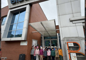 Grupa Motylków pozuje do zdjęcia pod wejściem do Biblioteki Miejskiej