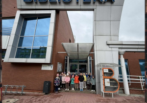 Grupa Smerfów pozuje do zdjęcia pod wejściem do Biblioteki Miejskiej