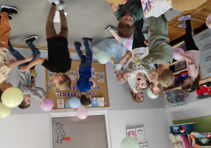 zdjęcie przedstawia chłopców i dziewczynki biegających po dywanie i odbijających balony.