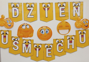 Tablica z napisem dzień uśmiechu i zdjęciami uśmiechniętych emotek.