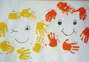 Dwie uśmiechnięte buzie wykonane z odbitych dłoni dzieci.