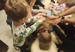 Na łóżku leży dziewczynka reszta dzieci ją masują.