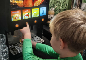 Chłopiec sam nalewa sobie sok z dystrybutora.