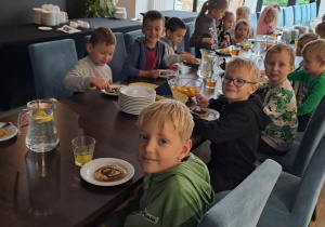 Dzieci z grupy Motylki siedzą przy stole na talerzach mają pankejki.