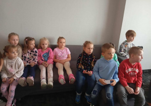 Dzieci z grupy Odkrywcy siedzą na narożniku w pokoju hotelowym.