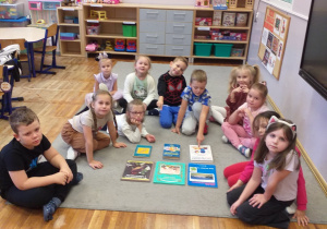 Zdjęcie przedstawia dzieci oglądające rozłożone przed nimi różnego rodzaju książki.