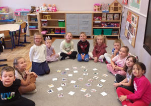 Zdjęcie przedstawia dzieci grające w grę Memory z obrazkami związanymi z edukacją.