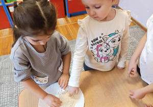 Dzieci sprawdzają poprzez dotyk jak wygląda mąka.