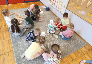 Dzieci w grupach wyciągają zawartość kopert i układają puzzle.