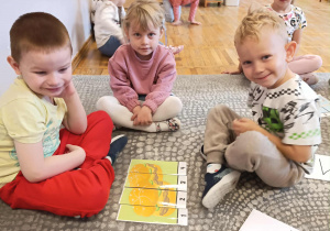 Troje dzieci prezentuje swój ułożony obrazek.