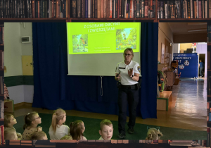 Pani Strażnik ze Straży Miejskiej opowiada dzieciom czego będzie dotyczyło spotkanie