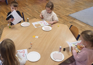 Dzieci siedzą przy stolikach, tworzą pracę plastyczną ,,Moja ulubiona kanapka”.