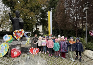 Smerfy pozują do zdjęcia przy pomniku Jana Pawła II.