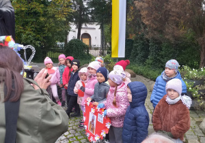 Dzieci z grupy Odkrywcy pozują do zdjęcia przy pomniku papieża Jana Pawła II.