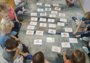 Dzieci siedzą na dywanie.