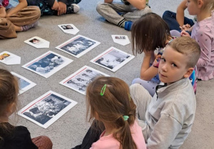 Motyki na dywanie oglądają zdjęcia sanitariuszek i łączniczek podczas swojej pracy.