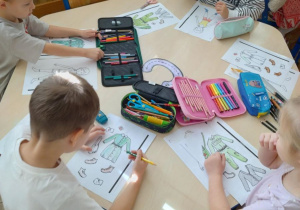 Smerfy przy stolikach wykonują prace plastyczną z ubiorem sanitariuszek i łączniczek.