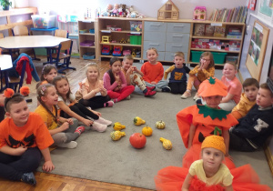 Zdjęcie przedstawia dzieci oglądające różne prawdziwe dynie.