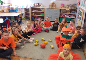 Zdjęcie przedstawia dzieci oglądające różne prawdziwe dynie.