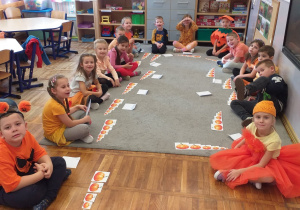 Zdjęcie przedstawia dzieci układające dynie od największej do najmniejszej.