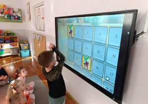 Chłopiec z grupy „Misie” rozwiązuje dyniowy quiz na tablicy multimedialnej.