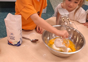 Dziewczynka wsypuje cukier do miski.