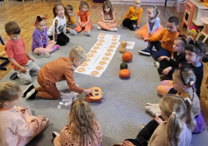 Chłopiec wrzuca do ,,dyni” odpowiednią ilość pestek.