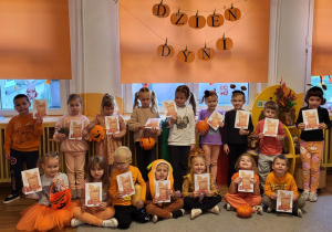 Dzieci pozują do wspólnego zdjęcia na tle dekoracji z napisem Dzień Dyni.