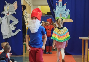 Chłopiec przebrany za Papę Smerfa idzie po czerwonym dywanie w bajkowym pokazie mody.