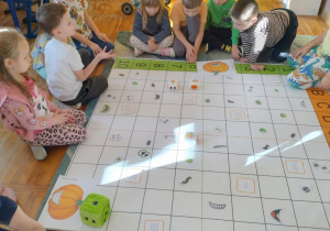 Na zdjęciu widać dzieci które bawią się na specjalnej macie do kodowania programując roboty Zosia aby zdobyć element swojej dyni.